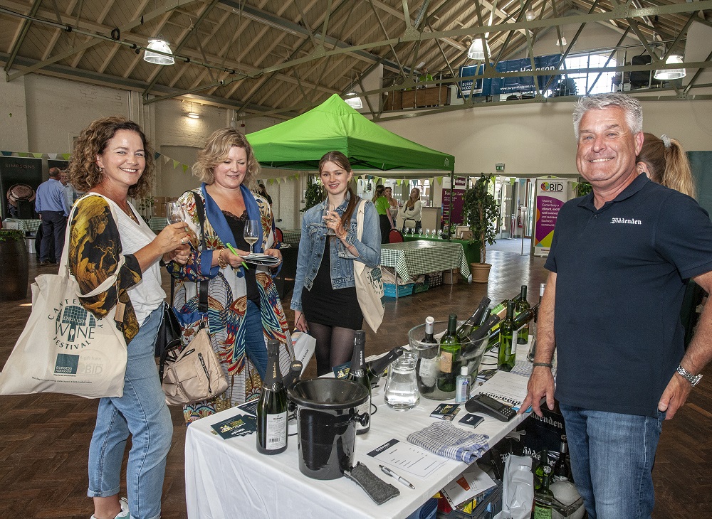 A group of women of mixed ages enjoyng the Canterbury Wine Festival, drinking samples from Biddenden vineyard