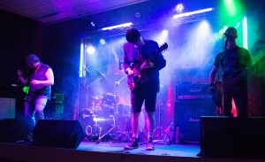 A performer on a stage with a guitar under blue lights