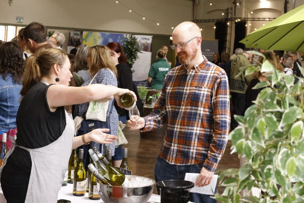 A photo of a man having a wine glass poured by a vineyard owner at Canterbury Wine Festoival.