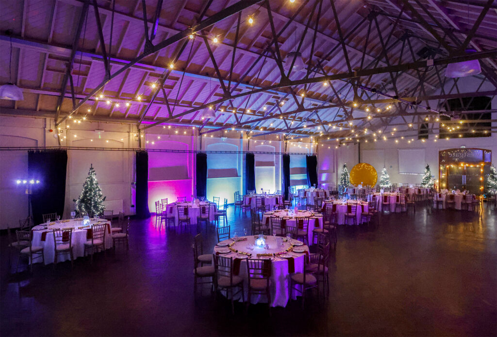 Westgate Hall Christmas Party Night - a large venue with festive decorations and party disco lights, with tables of 10 decorated ready for dinner.
