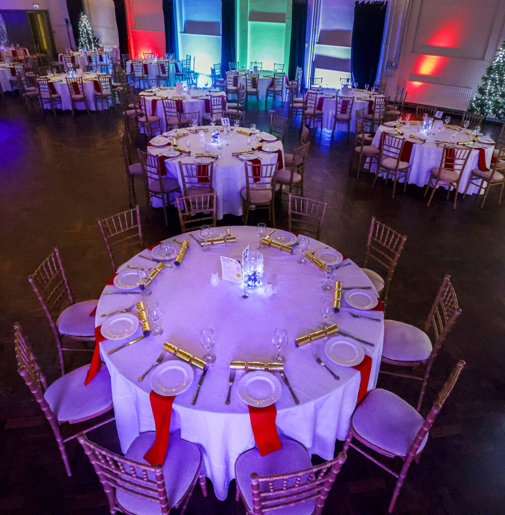 Westgate Hall Christmas Party Night - a large venue with festive decorations and party disco lights, with tables of 10 decorated ready for dinner.